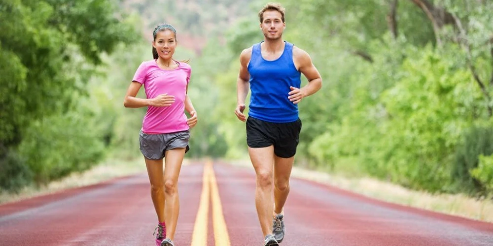 A man and woman jogging on a road, promoting physical health and mental health through exercise.