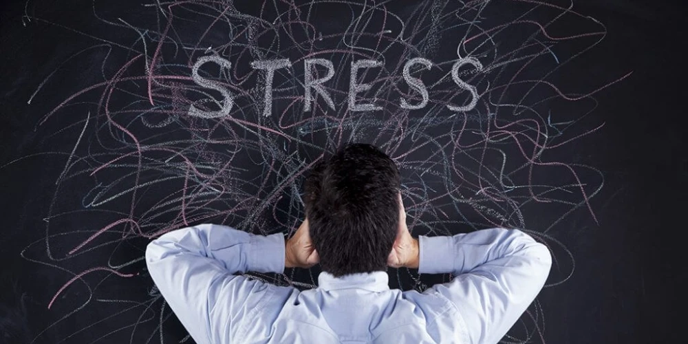 A man in front of a blackboard illustrating the impact of stress on hormones and health.