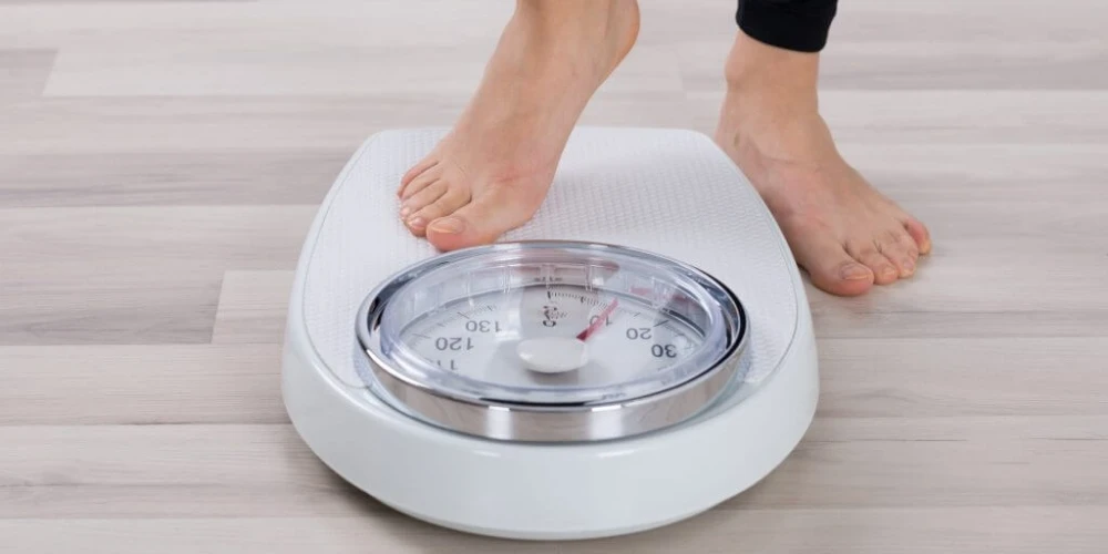 A woman's feet standing on a weight scale, highlighting physical health.