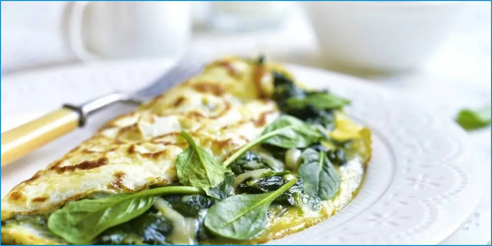 Spinach omelette on a plate with fresh herbs, perfect for athlete-friendly, high-protein recipes that boost performance.