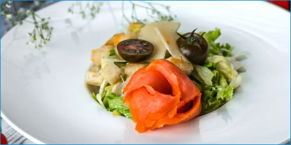 Gourmet salad with smoked salmon, fresh greens, and garnishes on a white plate, perfect for high-protein recipes.